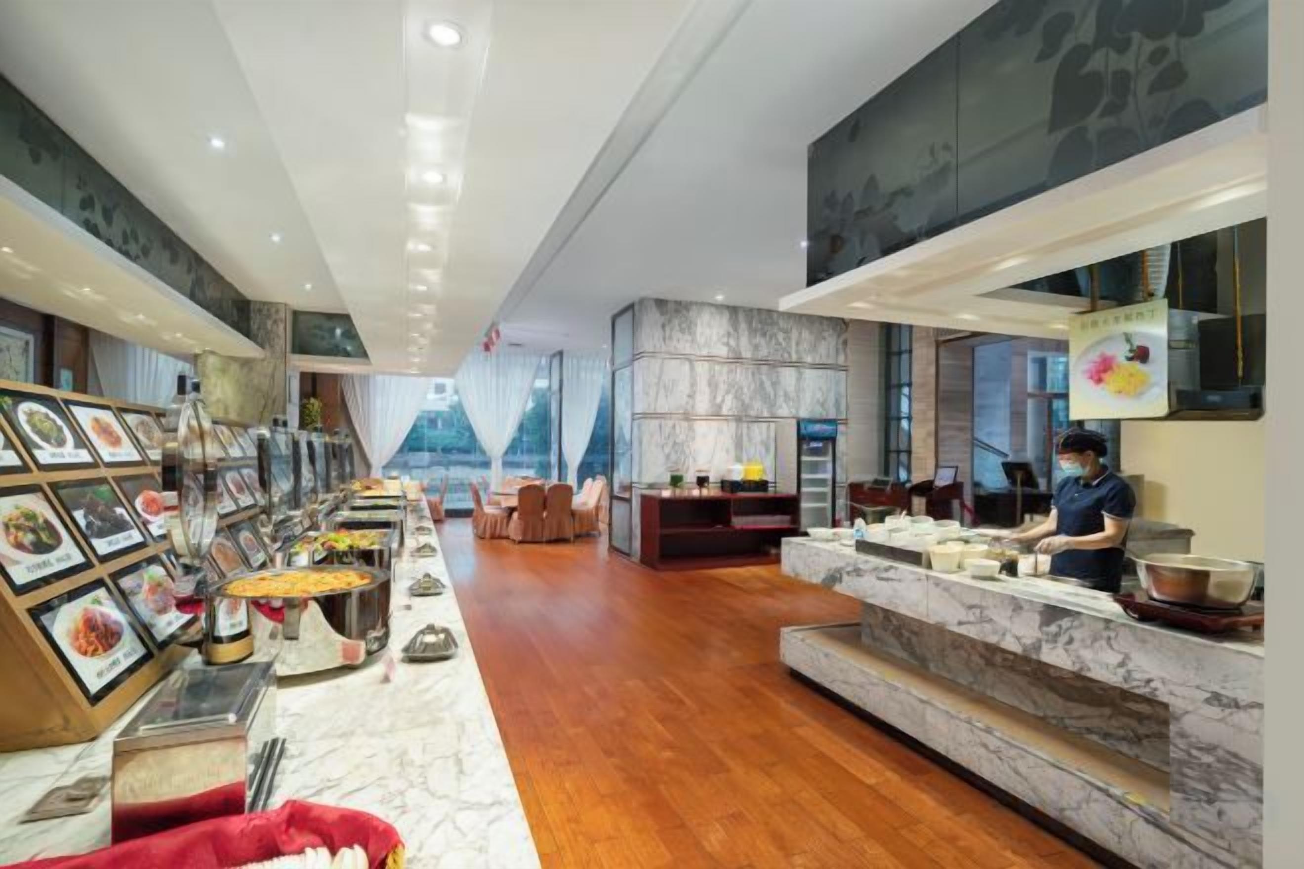 Vestíbulo de hotel con una recepción de mármol, zona de buffet y área de descanso con vistas.