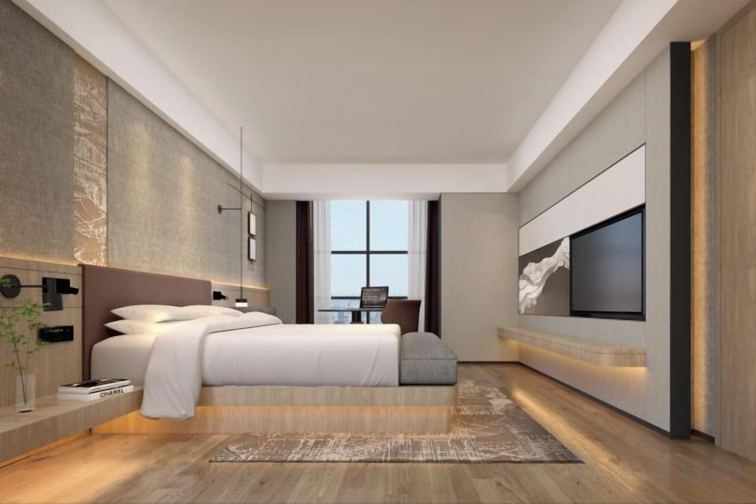 Une chambre moderne avec un grand lit, un téléviseur fixé au mur et une vue sur l’extérieur.