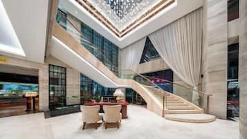 Un vestíbulo espacioso con una imponente escalera, un candelabro y una zona de estar.