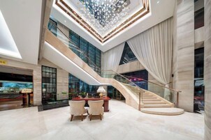Un vestíbulo espacioso con una imponente escalera, un candelabro y una zona de estar.