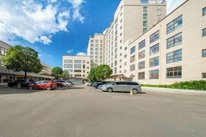 A parking lot with several cars, a building with multiple floors and large windows, and a clear blue sky. - Jinhua Kokusai Hotel (Pingxiang)