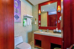 A bathroom with a wooden vanity, a large mirror, and a toilet. - Jinhua Kokusai Hotel (Pingxiang)