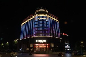 Un edificio con una entrada destacada y señalización, que presenta una estructura circular en la parte superior e iluminación vertical.