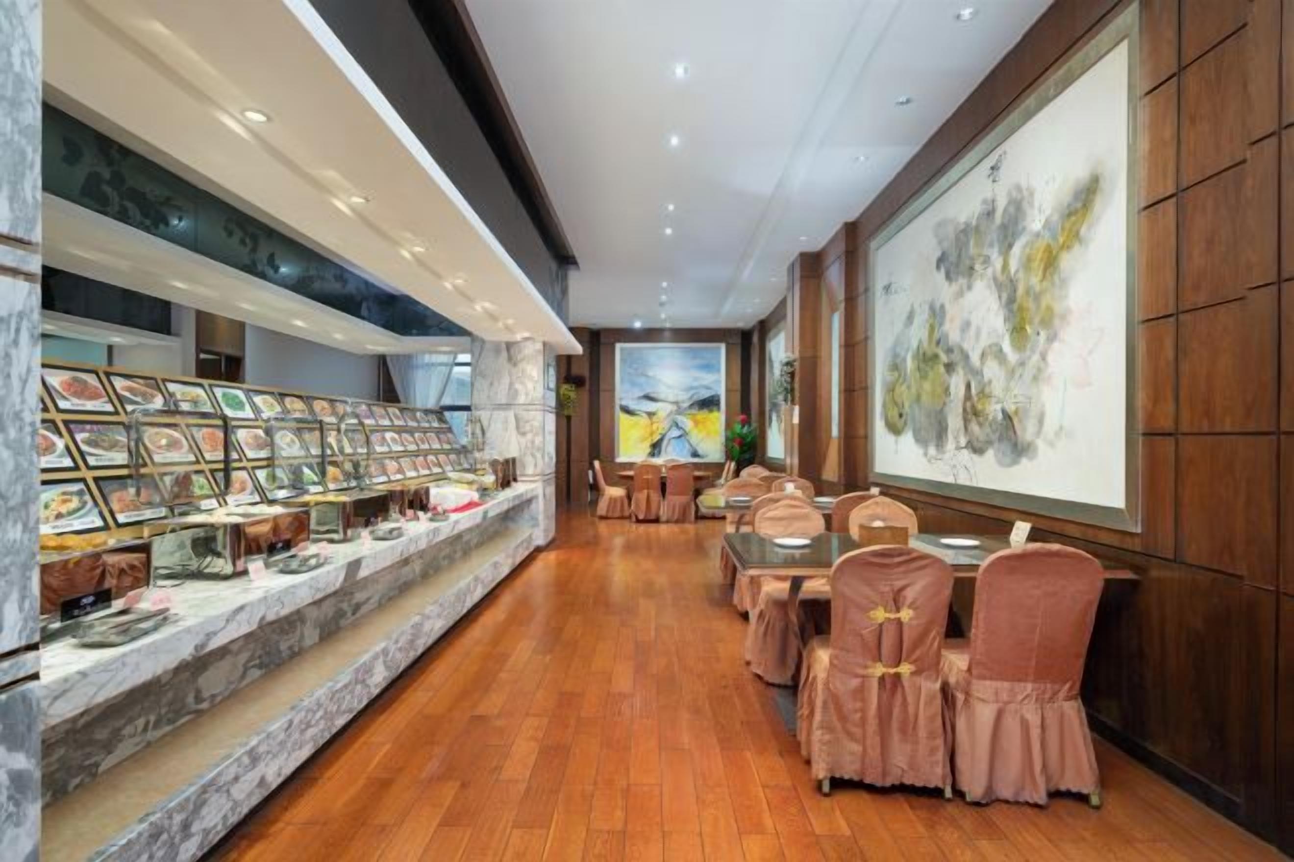 A hotel lobby with a marble reception desk, framed artwork, and a seating area with cushioned chairs.