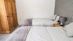 Een slaapkamer met twee bedden, een houten garderobe en een lamp.