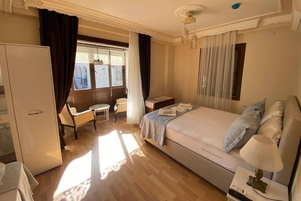 A hotel room with a bed, a desk, a chair, a wardrobe, and a window with curtains.