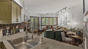 Une cuisine moderne dotée d’un grand îlot central, d’appareils électroménagers intégrés et d’un coin repas avec une table ronde et des chaises.