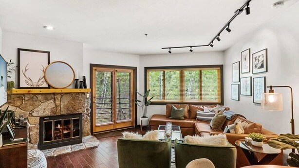 Un salon moderne avec une cheminée en pierre, de grandes fenêtres, un canapé en cuir et une table basse.
