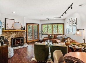 Un salon moderne avec une cheminée en pierre, de grandes fenêtres, un canapé en cuir et une table basse.