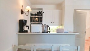 A compact kitchen with a white countertop, a coffee maker, a kettle, and a microwave. - 45 m2 house, facing the pine forest, terrace, garden and tranquillity (Mallemort)
