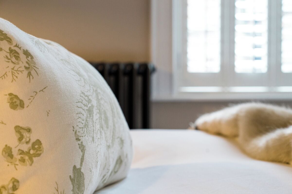Una cama con un cojín estampado de flores y una manta mullida.