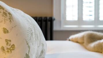 Una cama con un cojín estampado de flores y una manta mullida.
