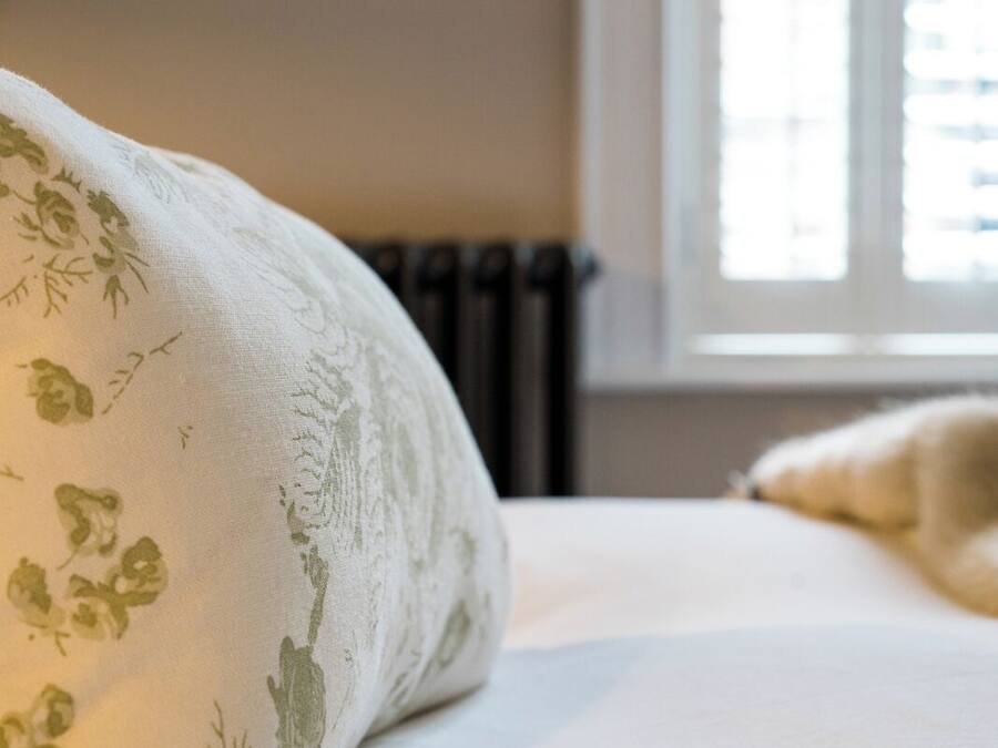 Een bed met een sierkussen met bloemenprint en een zachte deken.