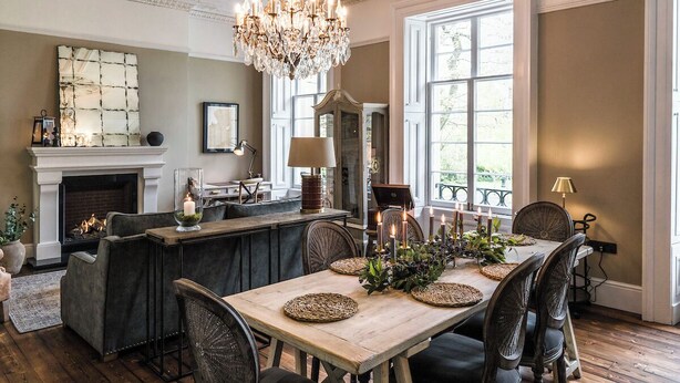 Un coin repas avec une table en bois, des chaises, un lustre et une cheminée.