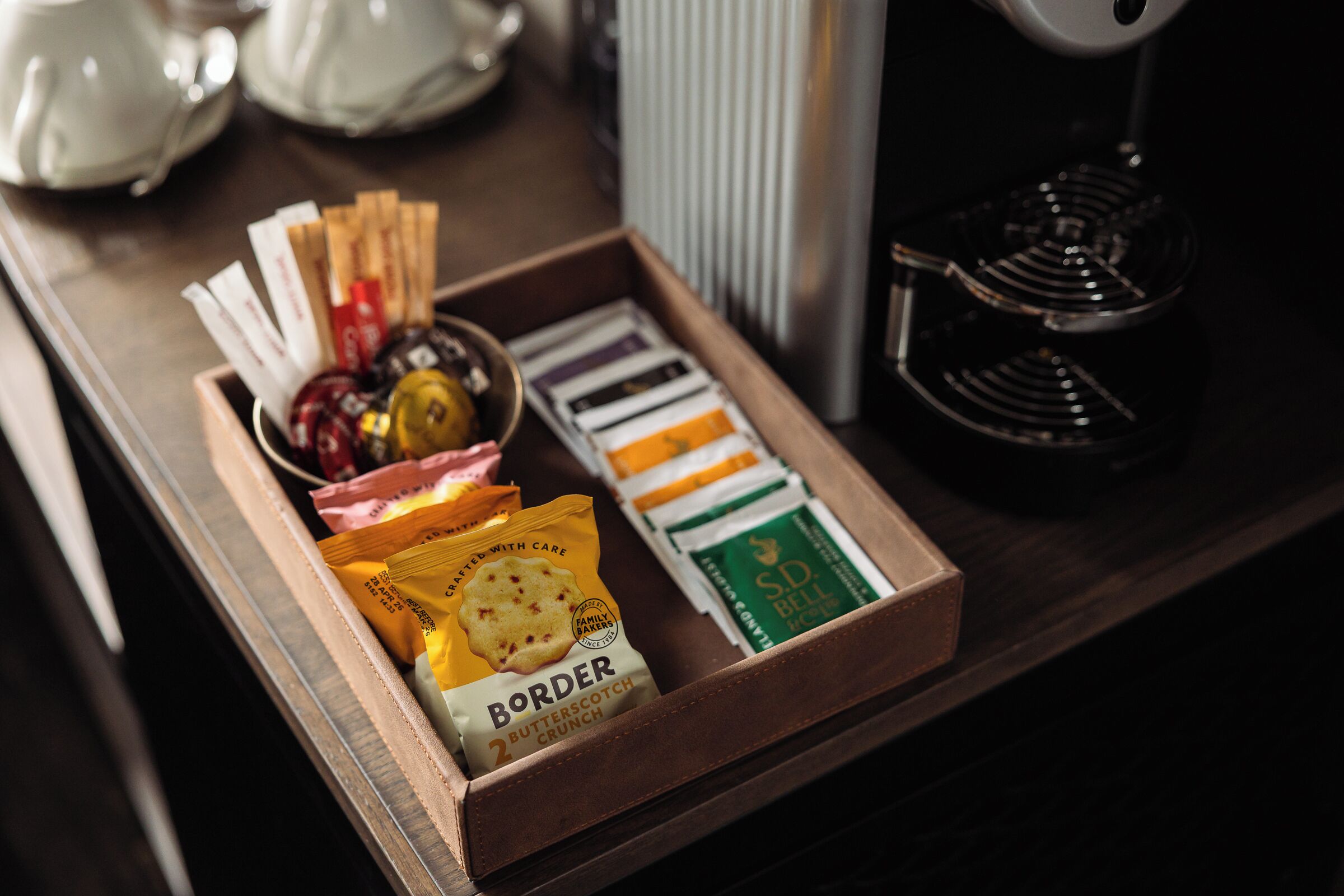 Una bandeja de madera con aperitivos y bolsitas de té sobre una mesa.