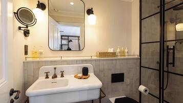 A bathroom with a white sink, two faucets, a mirror, and a glass shower enclosure.