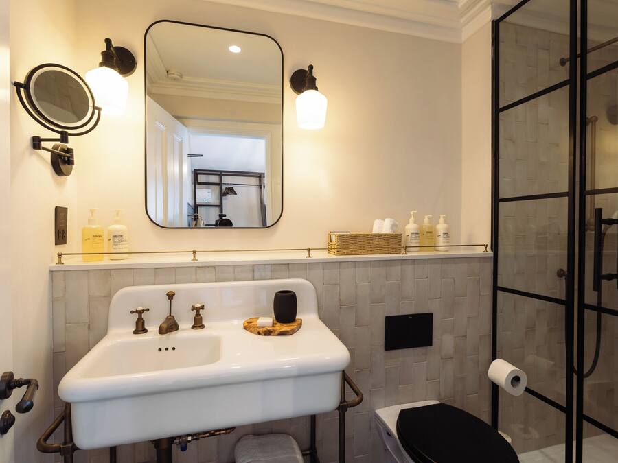 A bathroom with a white sink, two faucets, a mirror, and a glass shower enclosure.
