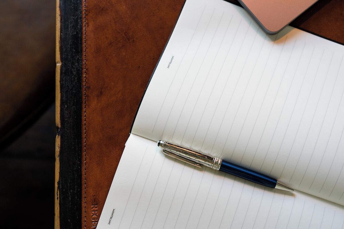 Un cuaderno con hojas rayadas y un bolígrafo sobre una superficie de madera.