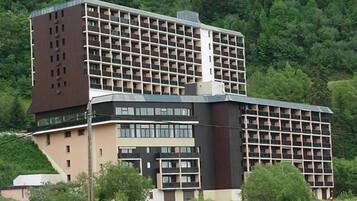 Un hotel de varios pisos con un diseño arquitectónico moderno, que presenta una combinación de balcones y ventanas amplias.