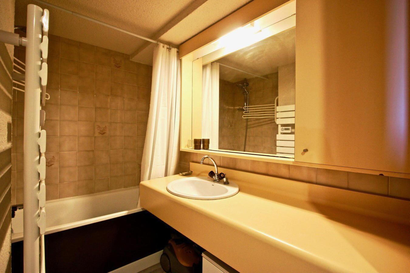 Une salle de bain avec un lavabo blanc, un miroir et un espace douche.