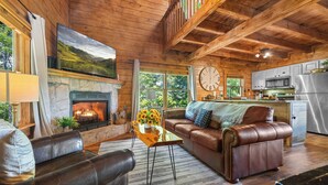 Ein gemütliches Blockhaus-Interieur mit Kamin, Ledersofa und Küchenzeile.