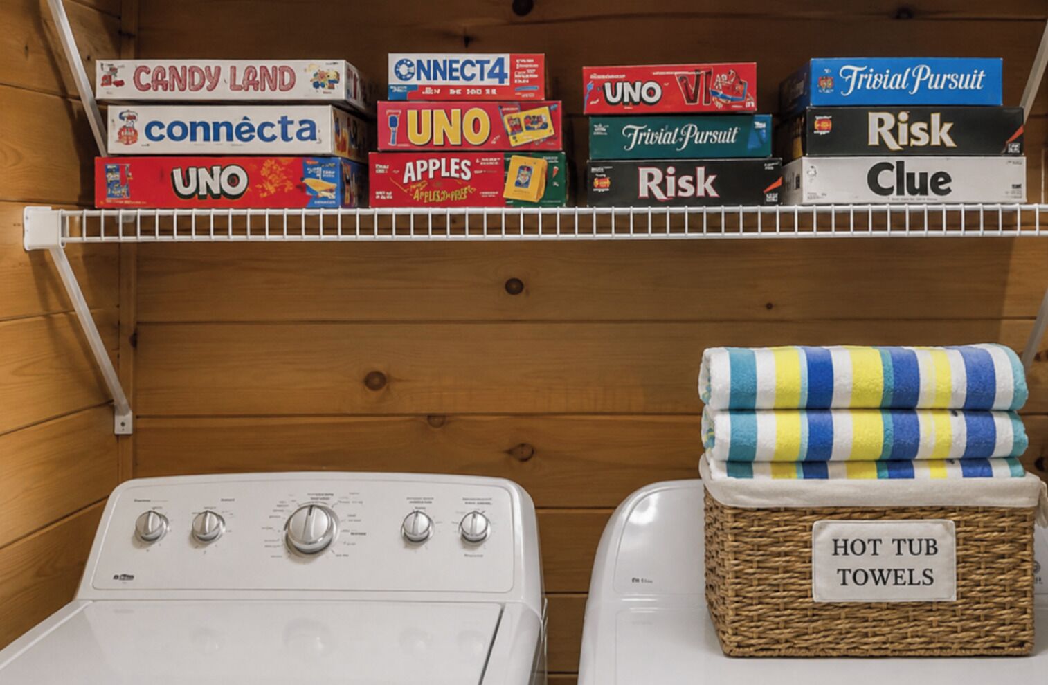 A laundry area with stacked board games and a basket labeled 'HOT TUB TOWELS'.