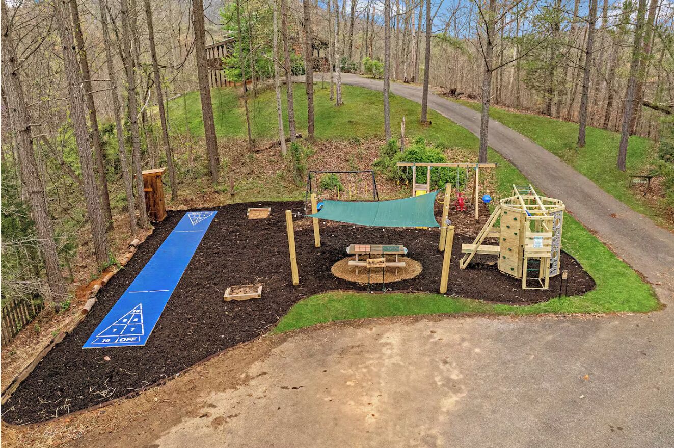 Ein Spielplatz mit einem blauen Sicherheitsweg, Holzspielgeräten und einem Picknicktisch.