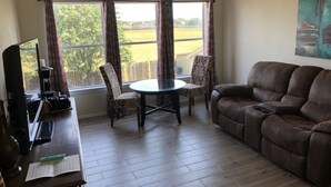 A living room with a brown leather sofa, a round table, and two patterned chairs. - Family-friendly 3 bedroom retreat, in shared house (Katy)