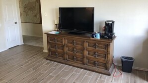 A living room with a flat-screen TV on a wooden cabinet, a coffee maker, and a trash bin. - Family-friendly 3 bedroom retreat, in shared house (Katy)