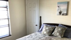 A bedroom with a bed, pillows, a door, and a window with blinds. - Family-friendly 3 bedroom retreat, in shared house (Katy)