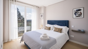 A bedroom with a large bed, a view of trees through a window, and a small shelf with decorative items. - PALACIO REAL - MADRID, 2HH, 2 BAÑOS, 6 PAX (Madrid)