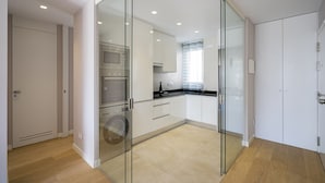 A modern kitchen with glass doors, white cabinets, and a black countertop. - PALACIO REAL - MADRID, 2HH, 2 BAÑOS, 6 PAX (Madrid)