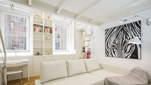 A modern living room with a white sofa, a bookshelf, and a zebra print artwork on the wall. - Apartamento Santa Engracia-Bilbao (Madrid)