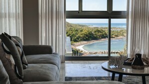 Un salón con un amplio ventanal que ofrece vistas a una playa y al océano.