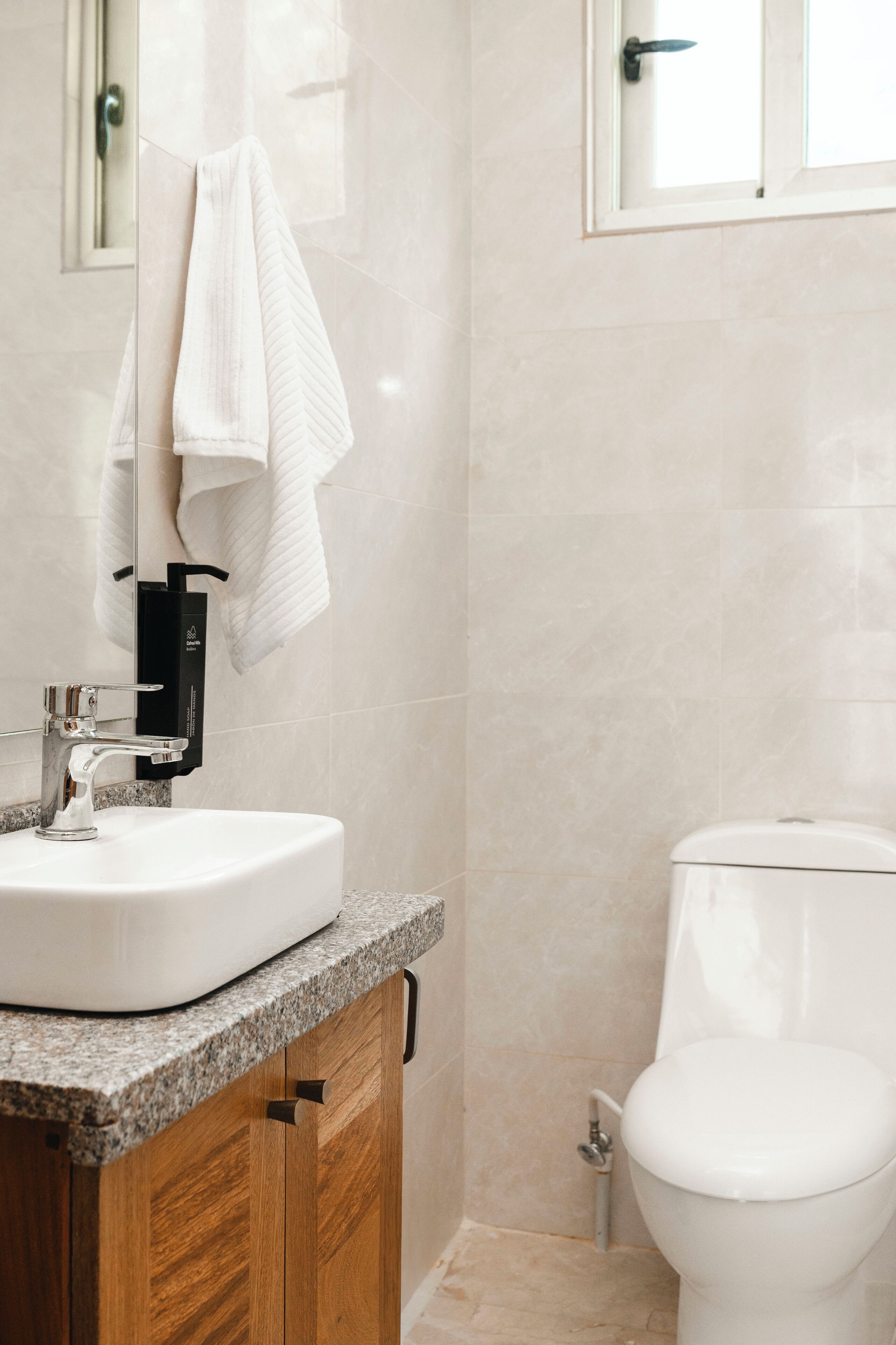 A bathroom with a white sink, wooden cabinet, and a toilet.