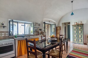 A kitchen with a dining table, chairs, a stove, and a window.