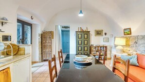 A dining area with a long table, chairs, a blue door, a cabinet with decorative items, and a lamp. - The Borgo Renaissance Stable (Farnese)