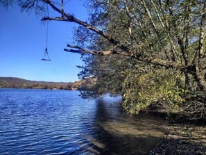 A serene lake with a clear view of the surrounding landscape, including trees and distant hills. - The donkey farm in Borgo Rinascimento (Farnese)