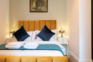 Una cama bien hecha con dos almohadas, cabecera y dos mesitas de noche con lámparas.