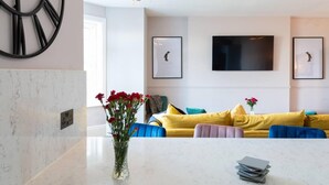 A modern living room with a yellow sofa, a coffee table with books, and a vase of flowers.