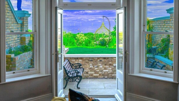 A room with a view of a garden, a bench, and a chair.