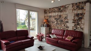Ein Wohnzimmer mit zwei roten Ledersofas, einem weißen Couchtisch und einer Steinwand.