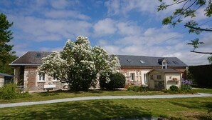 Ein zweistöckiges Haus mit einer Steinaußenfassade, ein großer blühender Baum davor und eine kleine angebaute Garage.