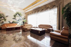 A spacious living room with a marble floor, leather sofas, a coffee table, and a large window with curtains. - Hedu Hotel (Dongguan Qiaotou) (Dongguan)