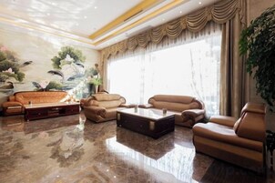 Un amplio salón con piso de mármol, sofás de cuero, una mesa de centro y un gran ventanal con cortinas.
