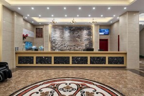 A hotel reception area with a marble counter, a television, and a decorative wall. - Hedu Hotel (Dongguan Qiaotou) (Dongguan)