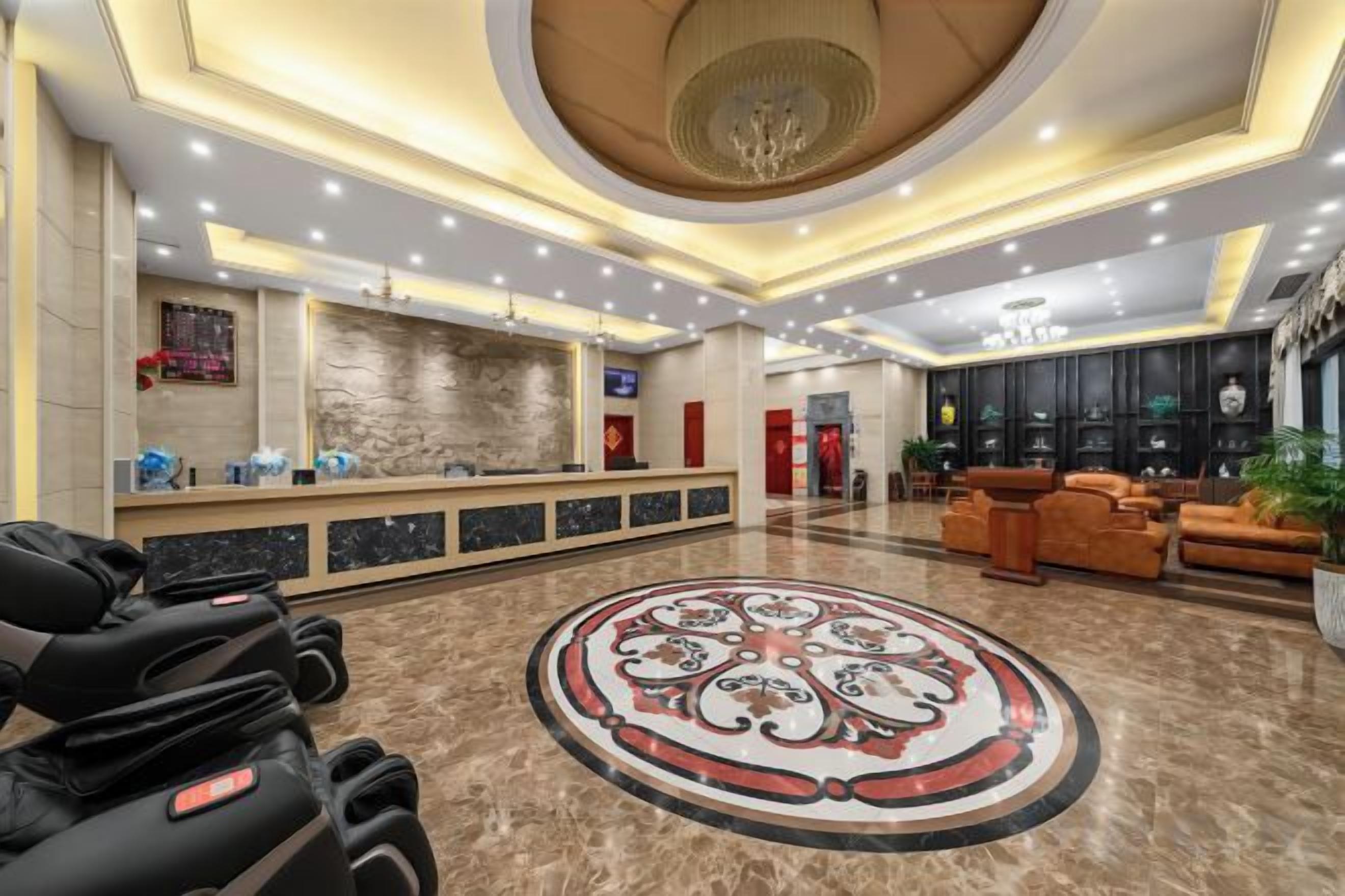 Um hall de hotel com balcão de recepção, área de estar e um padrão decorativo no chão.