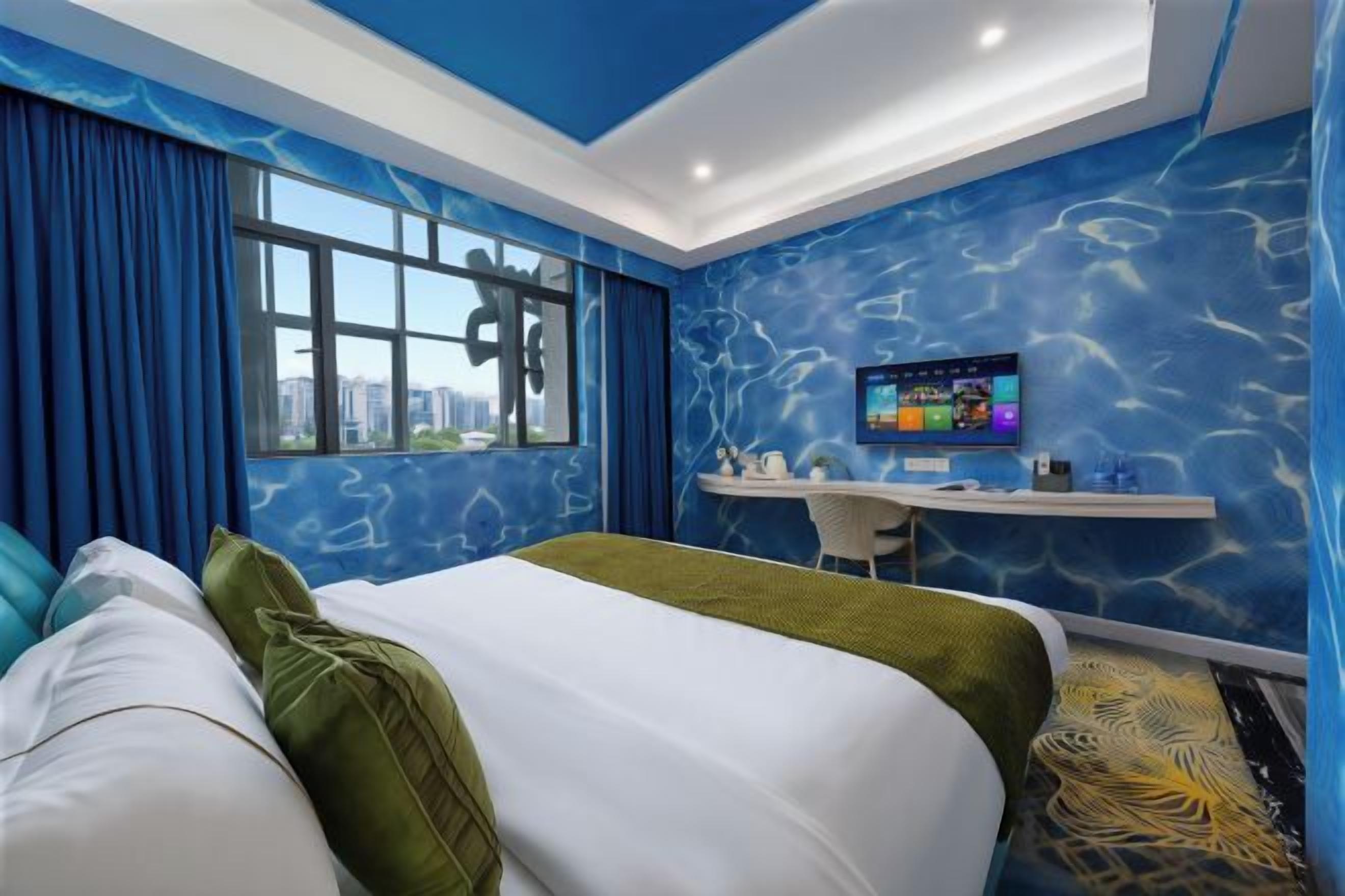 A hotel room with a bed, a desk, a chair, a TV, and a window with curtains.