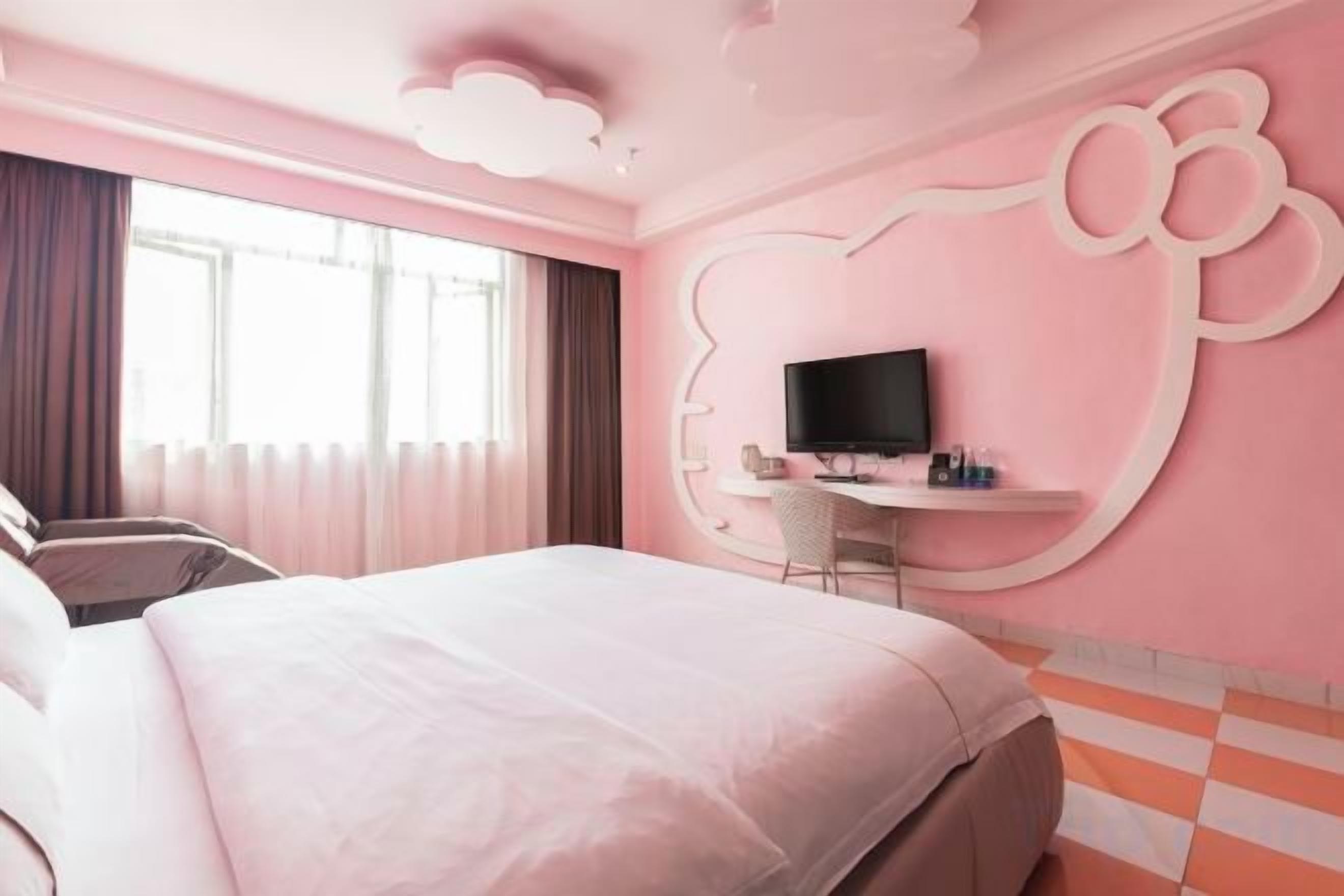 A hotel room with a large bed, a desk with a television, and a window with curtains.