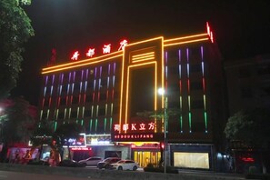 A building with illuminated signage and multiple storefronts at night. - Hedu Hotel (Dongguan Qiaotou) (Dongguan)